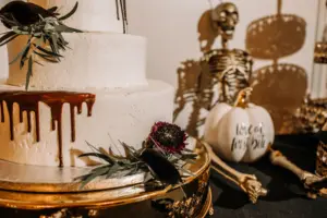Elegant Halloween Dessert Table Inspiration | Round Three-Tiered Buttercream Wedding Cake with Red Drips | Skull and Love at First Bite Pumpkin Table Decor Ideas