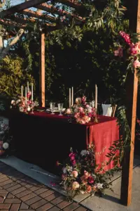Whimsical Boho Wedding Reception Sweetheart Table Under Pergola Decor Inspiration | Pink and Burgundy Roses, and Stock Flower Arrangement Ideas