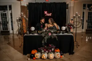 Spooky Halloween Inspired Black Wedding Reception Sweetheart Table Ideas | 'Til Death Neon Sign | Skulls and Pumpkin Centerpiece Decor Inspiration | Monogram Carved Pumpkins