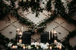 Custom Neon Sign with Lush Greenery Backdrop | Charcoal Plaid Wingback Chairs for Romantic Sweetheart Table Inspiration | White Orchids, Roses, and Greenery Garland Wedding Reception Decor Ideas | Tampa Bay Planner Wilder Mind Events