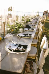 Glamorous Gold and Black Wedding Reception Table Setting Decor Ideas | Long Wooden Feasting Tables | Gold Glass Beaded Chargers with Menu Fold Napkins | Greenery Garland and Taper Candle Centerpiece Inspiration | Tampa Bay Videographer Shannon Kelly Films
