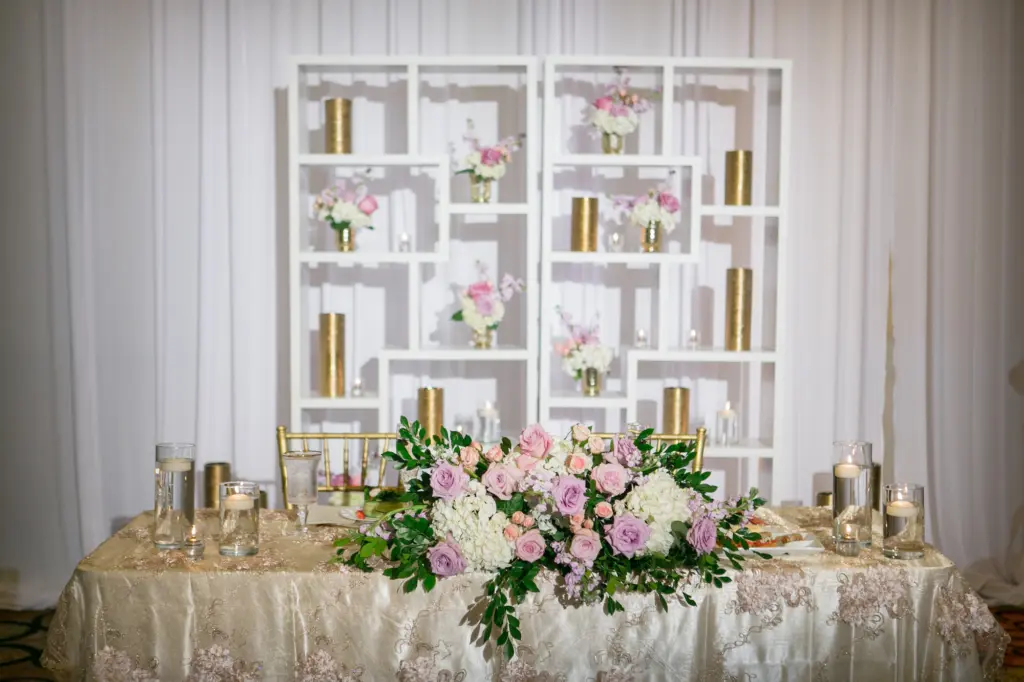 Elegant Gold Wedding Reception Sweetheart Table Decor Inspiration | Floating Candles, Gold Chiavari Chairs and Gold Vases | Pink and Purple Roses, Greenery, and White Hydrangeas | Tampa Bay Kate Ryan Event Rentals