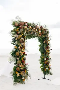 Fall Beach Wedding Ceremony Arch with White and Champagne Roses, Yellow Ranunculus, Palm Leaves, Monstera Leaves, Burgundy Chrysanthemums, Wine Hydrangeas