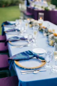 Jewel-Toned Blue Moody Fall Wedding Reception Table Decor Ideas | Blue Table Linen with Iridescent Napkin and Gold Glass Charger Place Setting