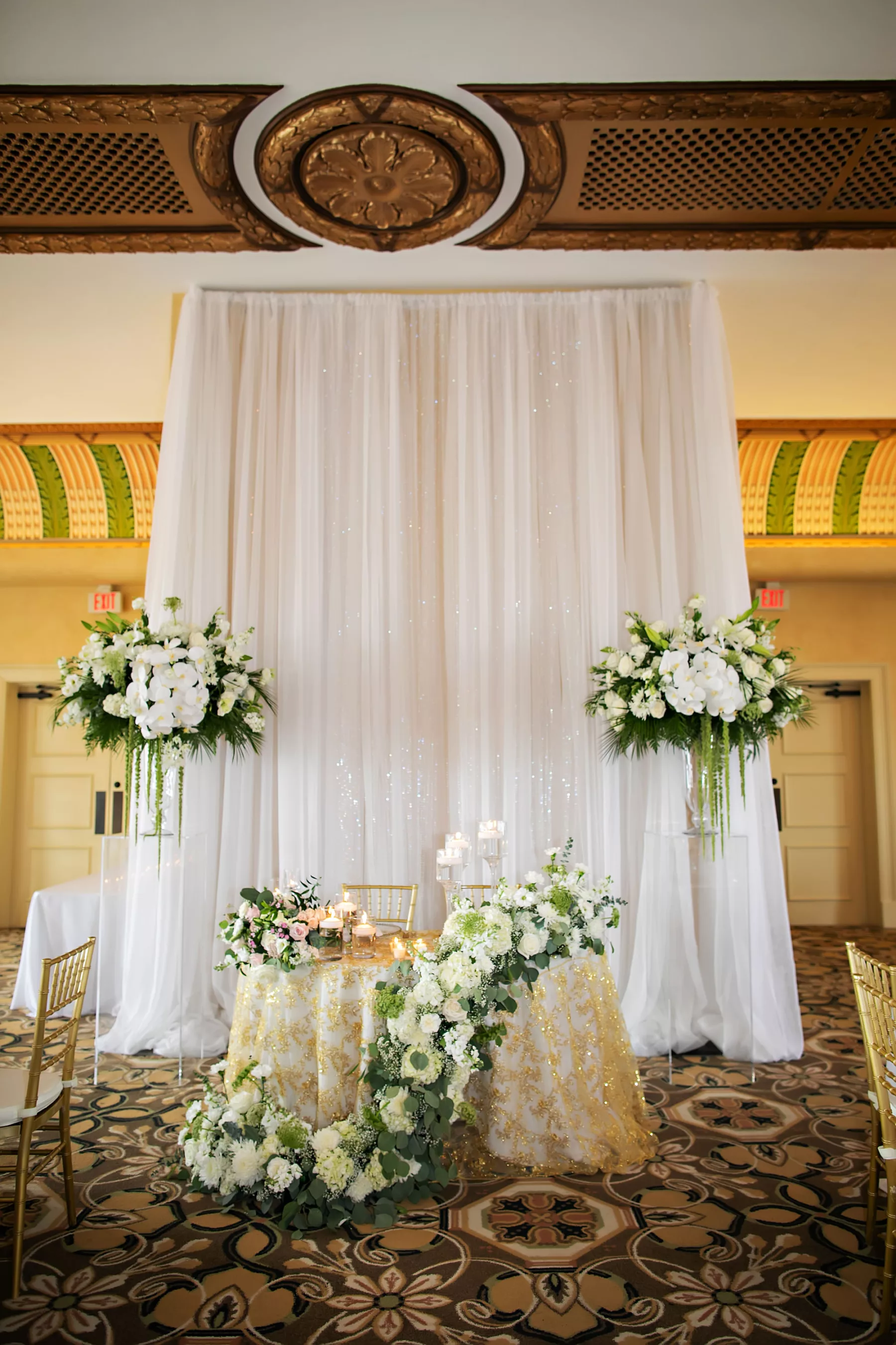 Classic White Wedding Reception Decor Ideas | White Drapery Sweetheart Table Backdrop Inspiration | Gold Sequin Tablecloth | White Orchid, Baby's Breath, Roses, and Greenery Floral Arrangement Ideas | Tampa Bay Event Planner Coastal Coordinating