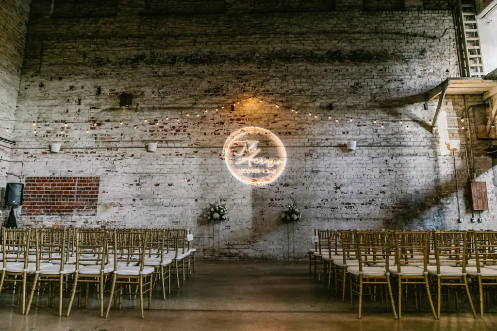 Timeless Industrial Wedding Ceremony with White Washed Brick Wall Backdrop Decor Ideas | Name Projector Inspiration | Gold Chiavari Chairs | Tampa Bay Rental Company A Chair Affair | Downtown Tampa Event Venue The Rialto