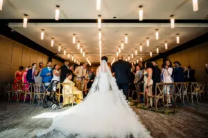 Bride and Father Walking Down Wedding Ceremony Aisle | One Shoulder Tulle Mermaid Pantora Bridal Wedding Dress Ideas |. Tampa Videographer Priceless Studio Design | Downtown Tampa Heights Event Venue Armature Works Indoor Ceremony