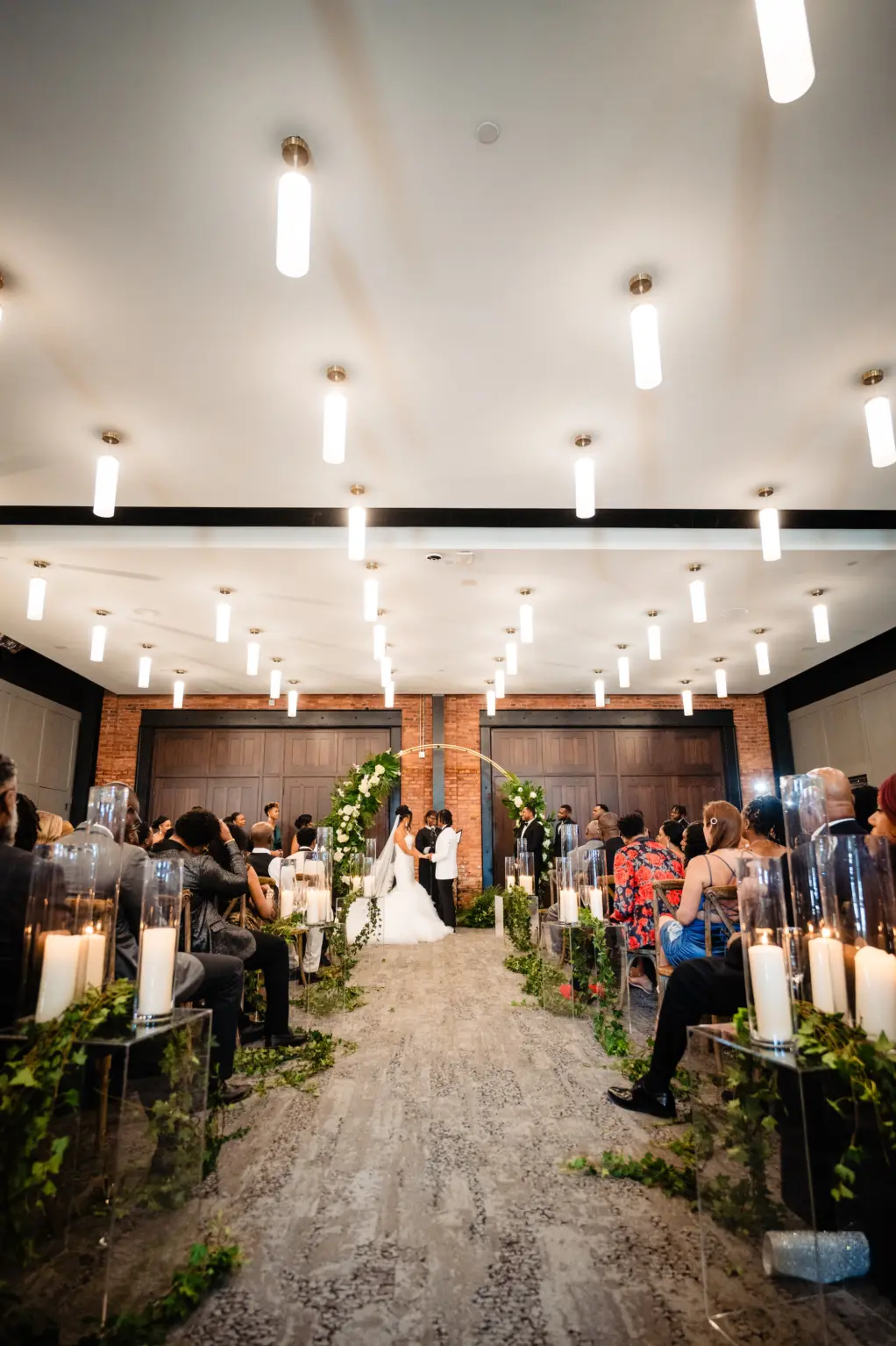 Elegant Indoor Industrial Wedding Ceremony with Pillar Candle Aisle Decor Inspiration | Round Gold Arch Ideas | Tampa Heights Event Venue Armature Works