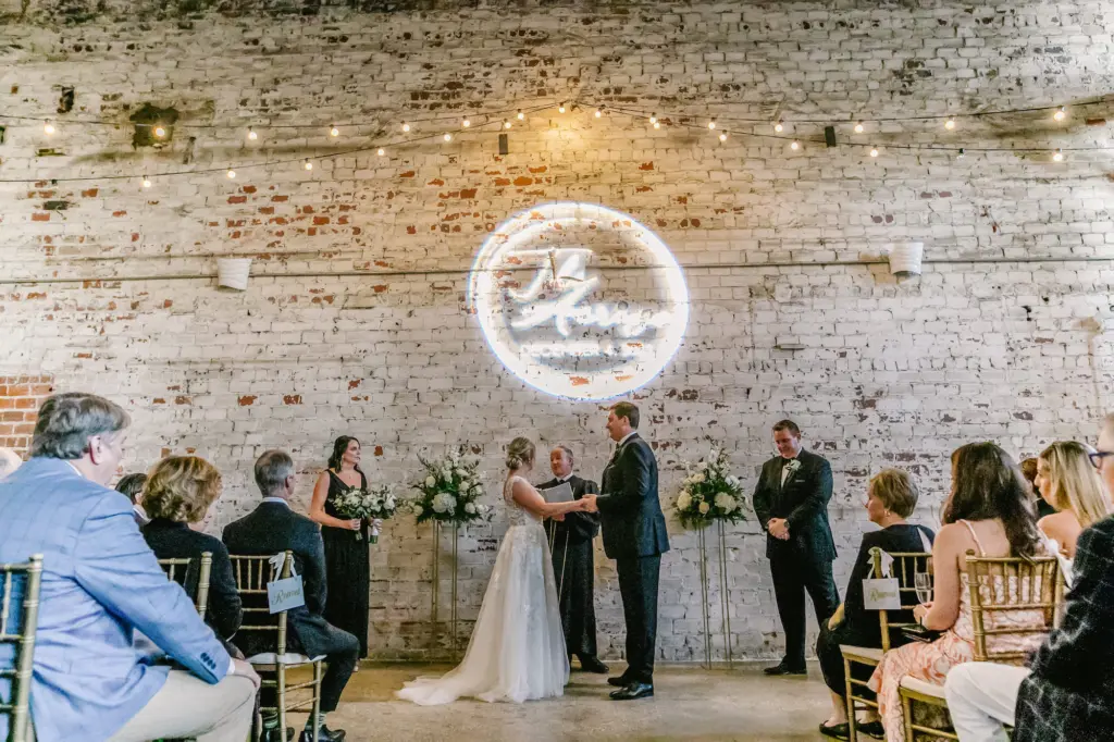 Timeless Industrial Wedding Ceremony Decor Inspiration | White Washed Brick Wall with Name Projector Ideas | Downtown Tampa Heights Event Venue The Rialto Theatre | Wedding Gobo Projection Grant Hemond & Associates