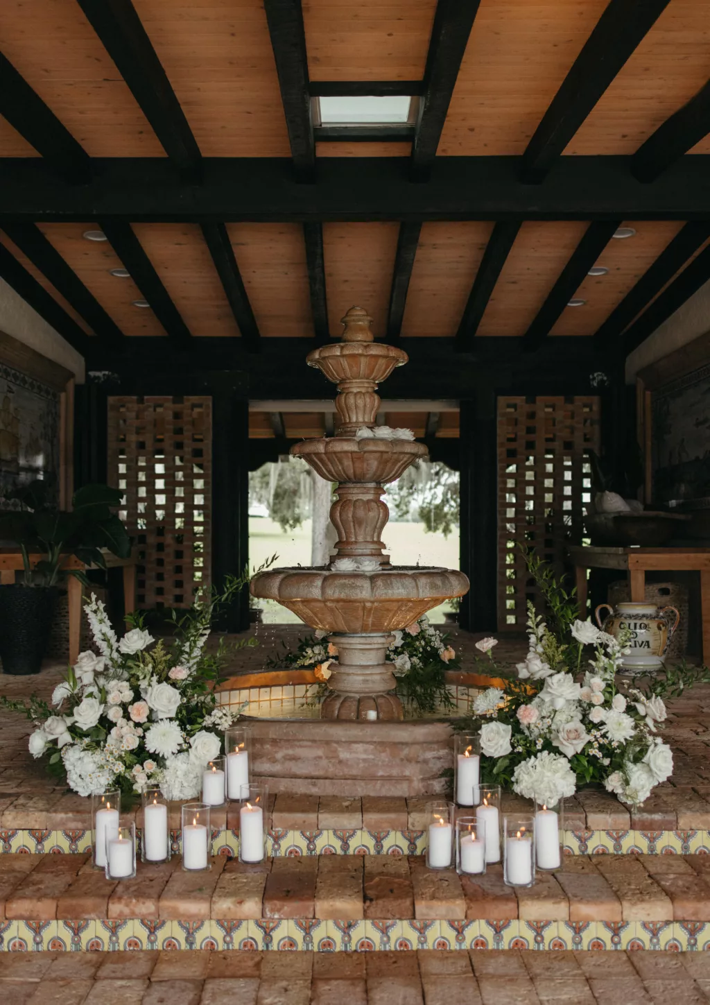 Spanish Style Fountain at Tampa Bay Event Venue La Hacienda on Snow Hill | Candlelit Wedding Venue Entrance Decor Ideas | White Roses, Hydrangeas, Chrysanthemums, Feverfew Daisies, Stock Flowers, and Greenery