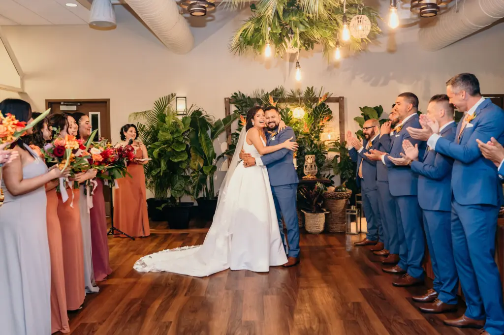 Bride and Groom Just Married | Indoor Tropical Wedding Ceremony Decor Ideas | Blue Suit Groomsmen Attire Inspiration | Mismatched Taupe Beige and Burnt Orange Bridesmaid Dresses
