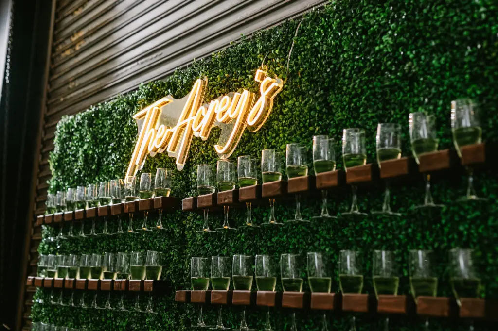 Hedge Wall with Champagne Glasses | Custom Neon Sign for Wedding Reception Cocktail Hour Decor Ideas | Tampa Event Rentals A Chair Affair