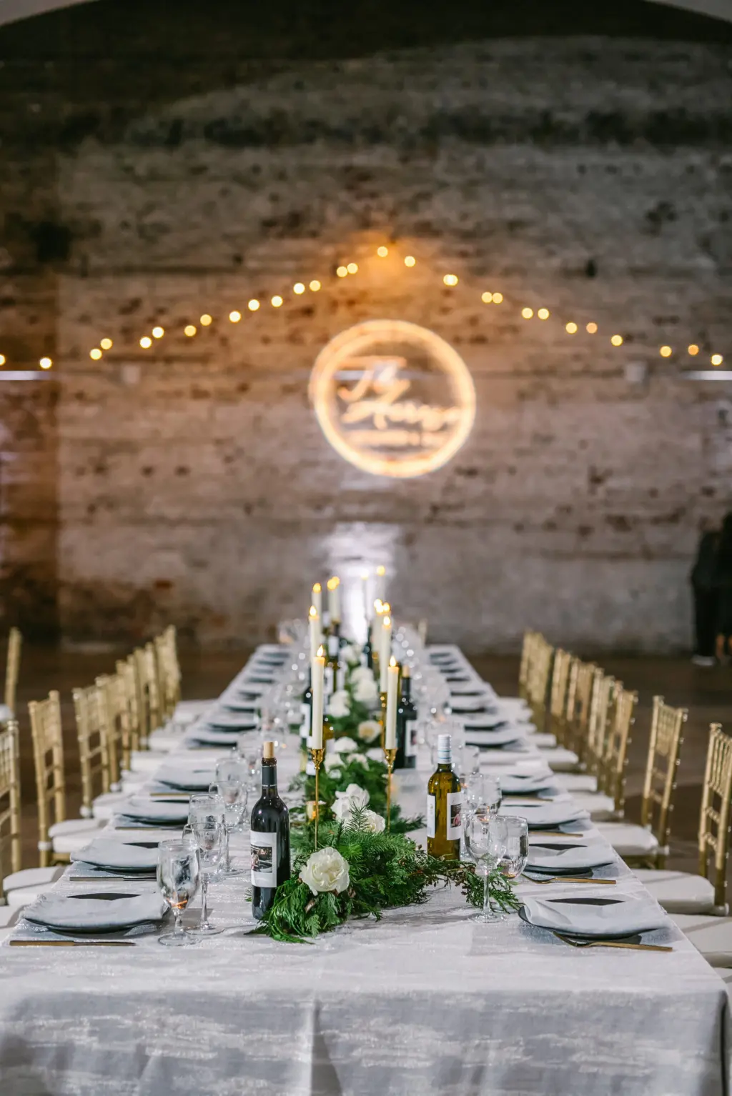 Classic Black and White Wedding Reception Decor Ideas | Long Feasting Tables | Greenery Garland and Taper Candles with Gold Holders Centerpiece Inspiration | Personalized Wine Bottles for Guests | Tampa Bay Rental Company A Chair Affair