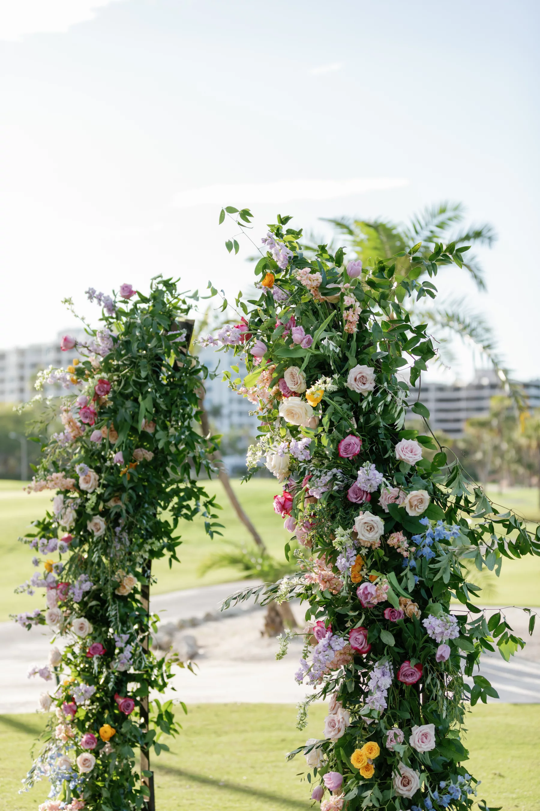 Whimsical Pastel Wildflower Outdoor Spring Wedding Ceremony Arch Decor Inspiration | Pink, Yellow, and White Roses, Purple Tulips, Ranunculus and Greenery Ideas