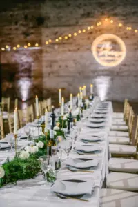 Classic Black and White Wedding Reception Decor Ideas | Greenery Garland and Taper Candles with Gold Holders Centerpiece Inspiration | Personalized Wine Bottles for Guests | Tampa Bay Rental Company A Chair Affair
