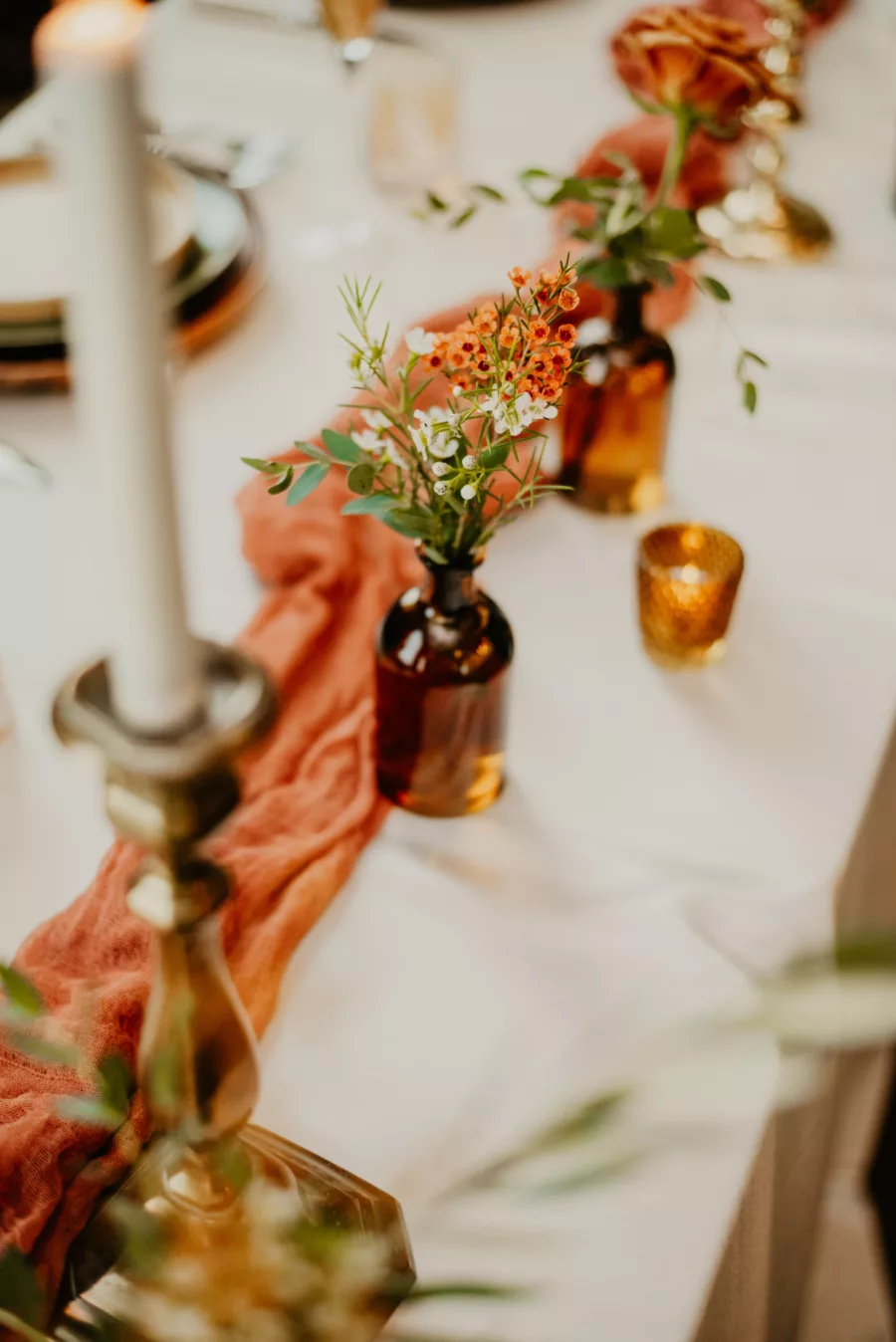 Boho Wedding Reception Centerpiece Ideas | Terracotta Cheescloth | Amber Bud Vases with Orange and White Alyssum | White Taper Candles