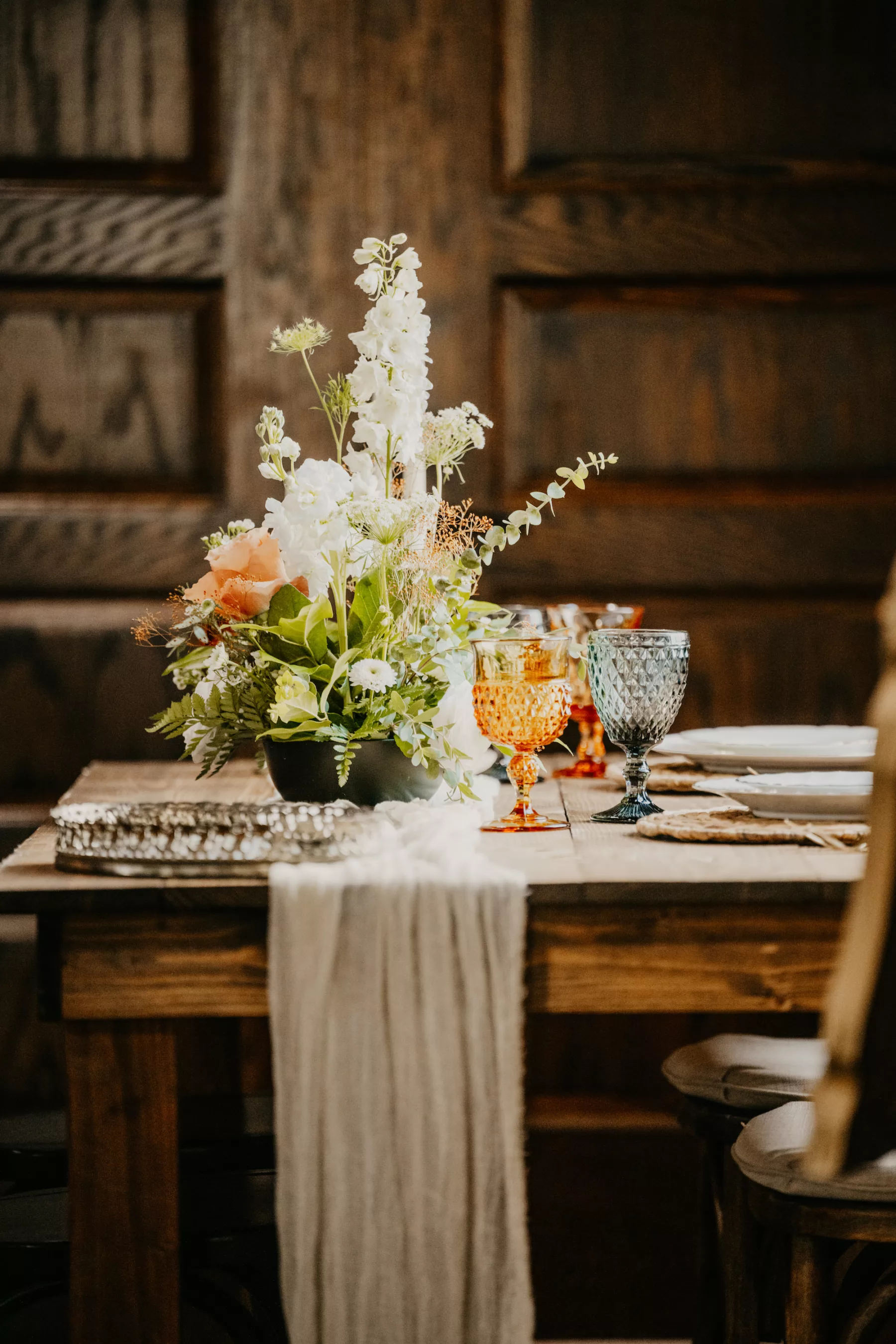 Boho Wedding Reception Decor Inspiration | Colored Glass Goblets | White Campanula, Orange Roses, Eucalyptus, and Greenery Centerpiece Ideas