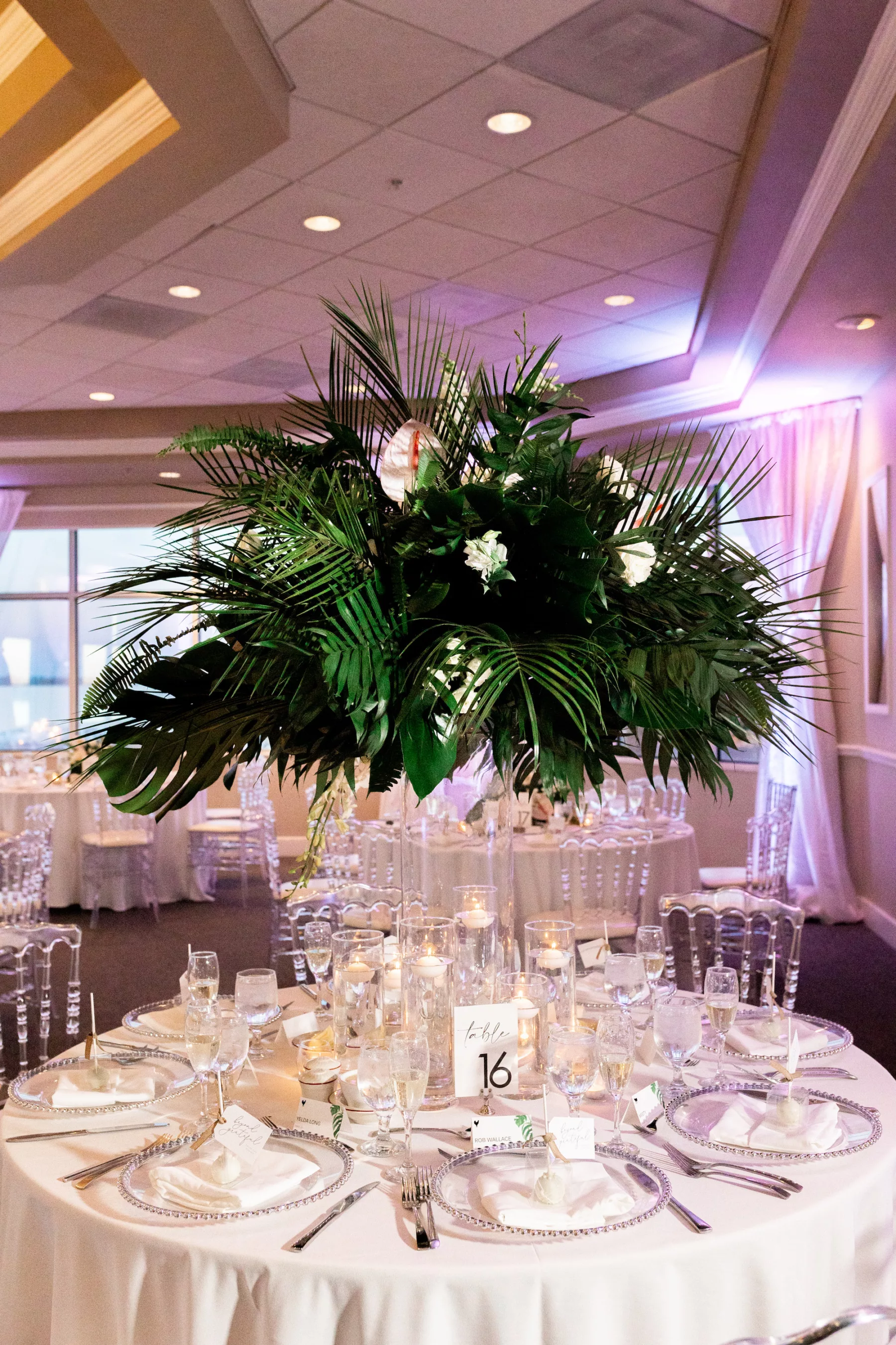 Modern White Wedding Reception with Tall Tropical Floral Centerpiece Arrangement | Monstera Leaves, Palm Fronds, White Anthurium and Roses