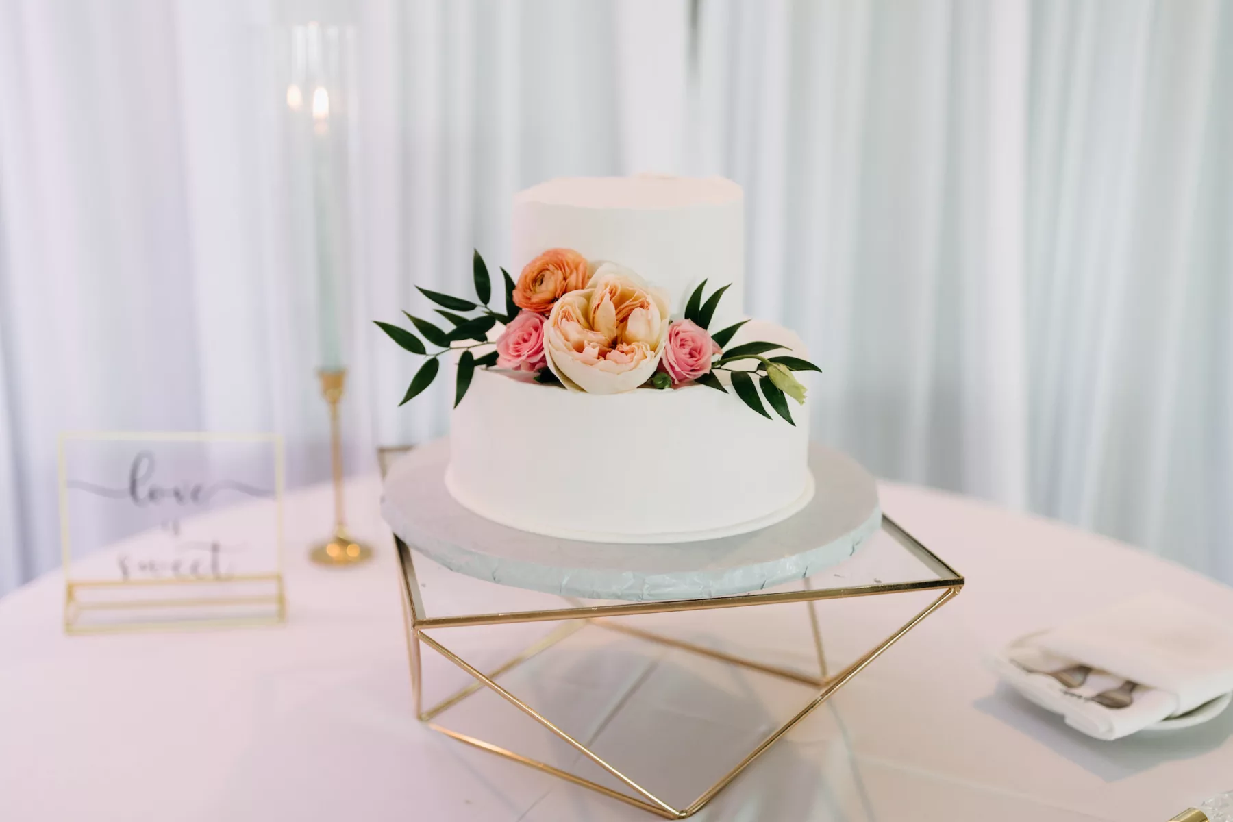 Two-Tiered Round Wedding Cake with Pink Garden Rose, Orange Ranunculus, And Greenery Accents on Geometric Cake Stand Ideas
