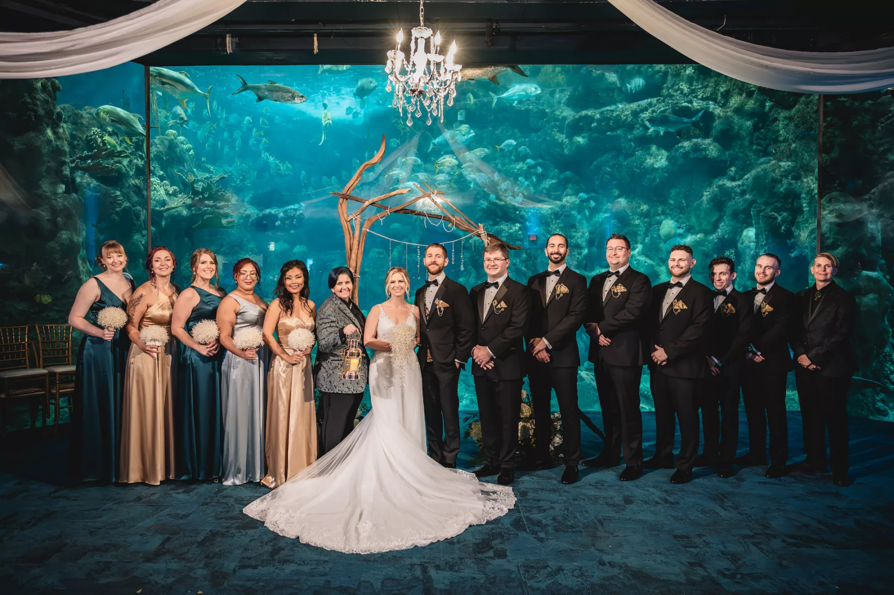 Mismatched Emerald, Sage, and Gold Satin Floor Length Bridesmaid Dress Ideas | Unique Pearl Bridal Bouquet Inspiration | Ivory A Line Lace and Tulle Morilee Wedding Dress | Black Tuxedo Groomsmen Wedding Attire | Coral Reef Gallery | Event Venue The Florida Aquarium