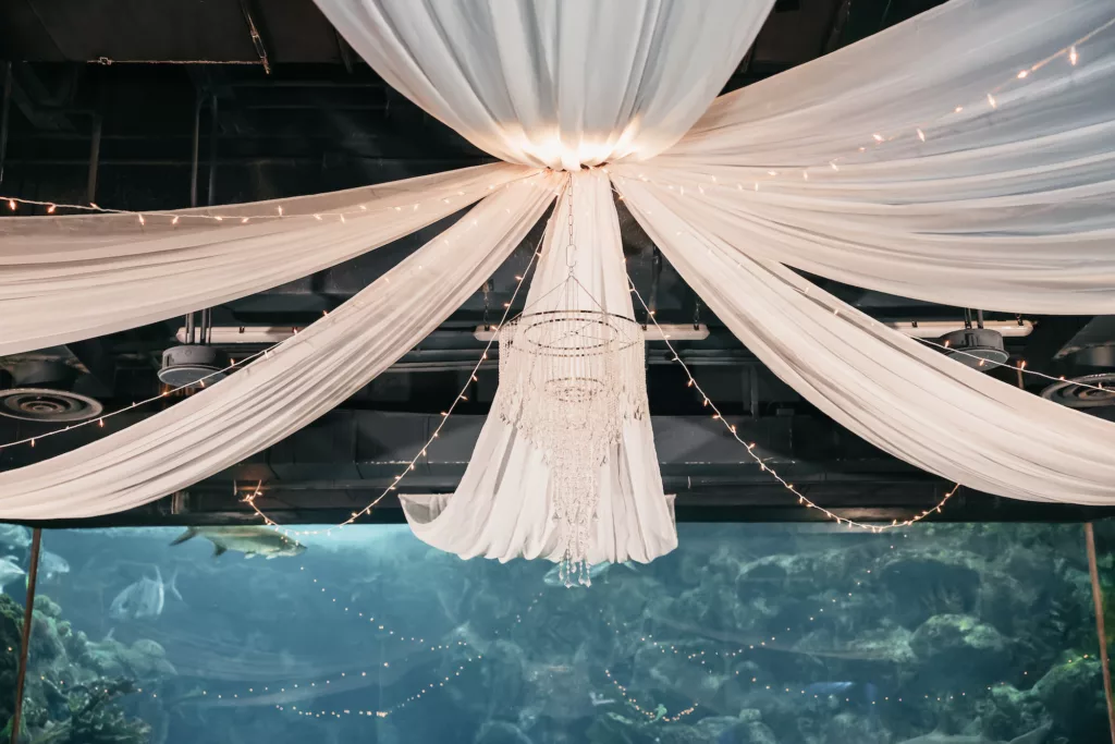 White Drapery with Crystal Chandelier and String Lights Wedding Ceremony Decor Ideas | Tampa Bay Event Venue The Florida Aquarium
