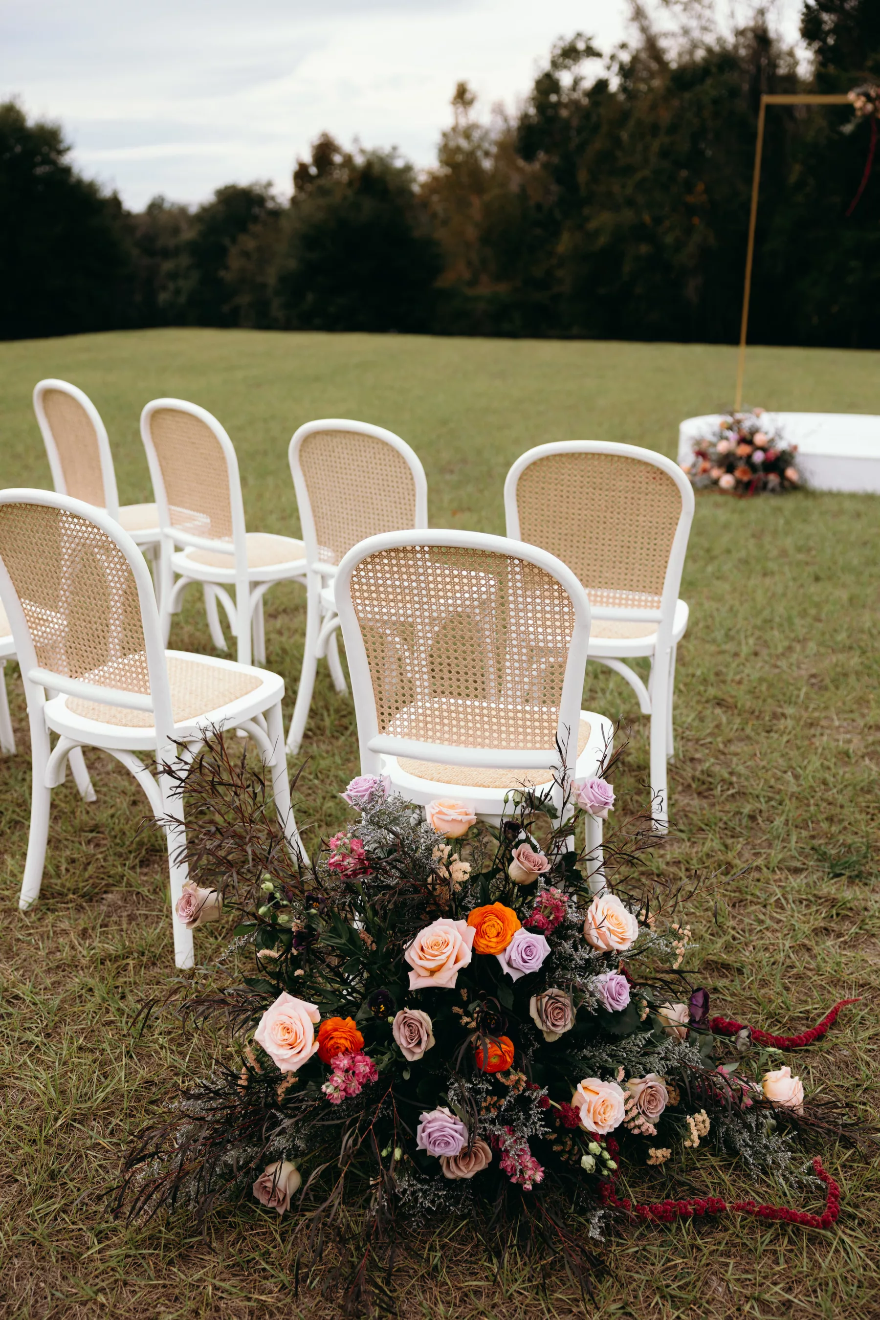 Moody Purple and Peach Whimsical Outdoor Field Wedding Ceremony Inspiration | White and Rattan Chair Ideas | Pink, Orange, Purple, and White Roses, Amaranthus, and Greenery Aisle Decor | Tampa Bay Event Venue La Hacienda At Snow Hill | Planner MDP Events | Florist Save The Date Florida