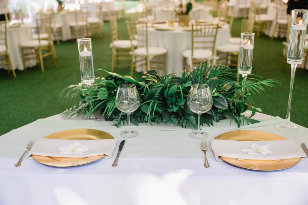 White and Gold Wedding Reception Sweetheart Table Decor Inspiration | Floating Candles, Tropical Greenery Tabletop Arrangement with Palm Fronds and Ferns Ideas | Tampa Bay Caterer Olympia Catering