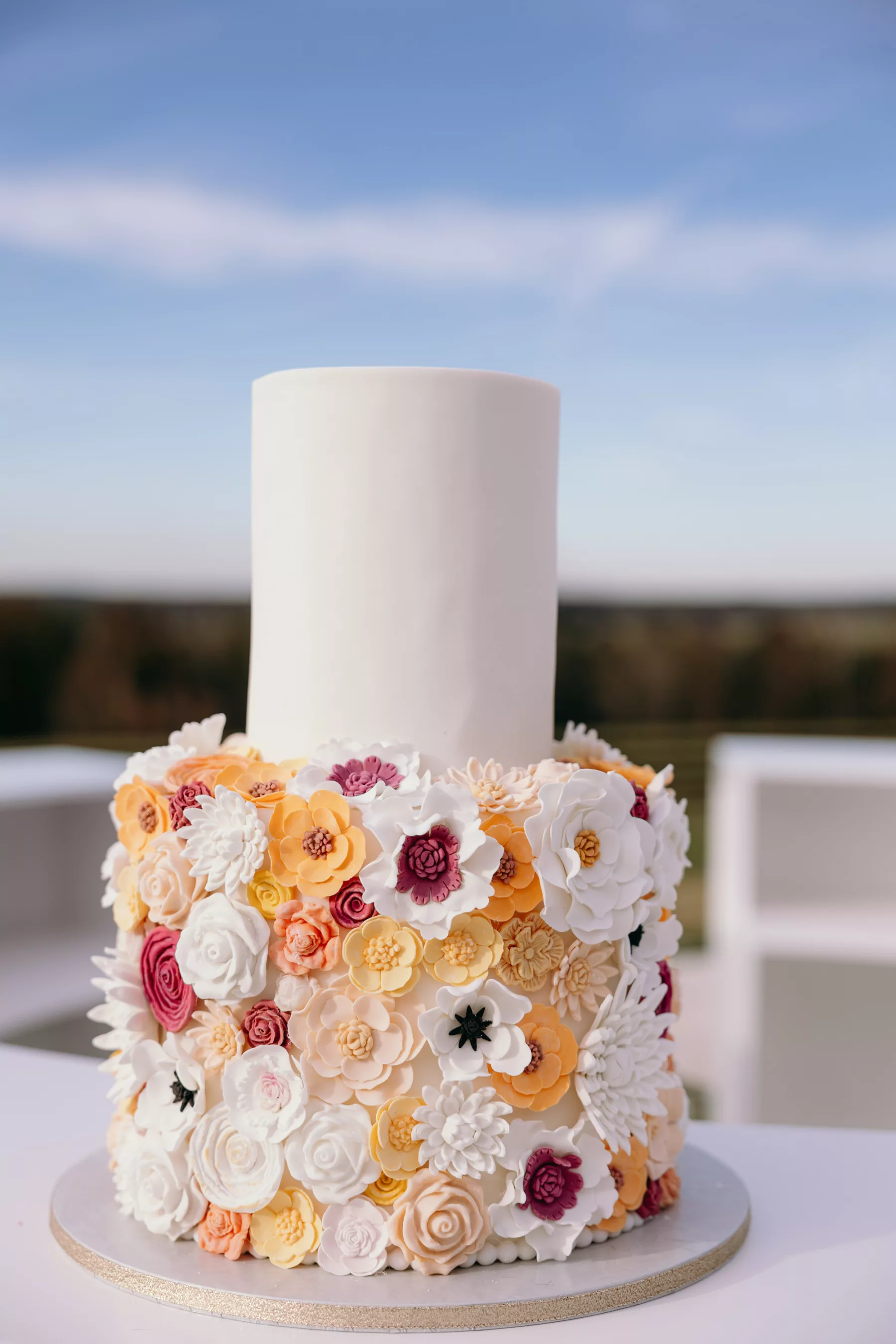 Whimsical Two-Tiered Wedding Cake with Yellow, White, and Mauve Sugar Flowers