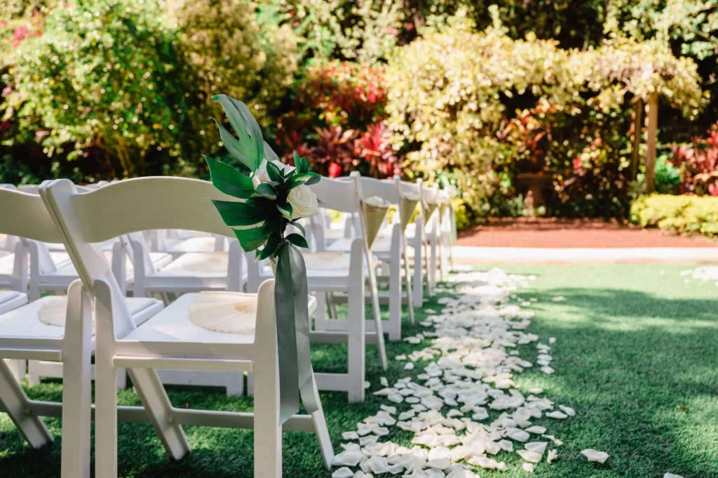 Folding Garden Chairs for Outdoor Wedding Ceremony with Monstera Leaf and White Rose Aisle Decor Inspiration