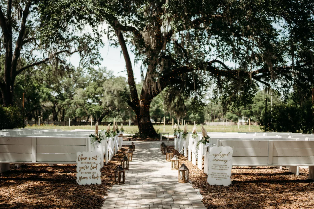 Outdoor Oak Tree Spring Boho Wedding Ceremony Decor with White Church Pews Inspiration | Florida Event Venue Ever After Farms Flower Wedding Barn