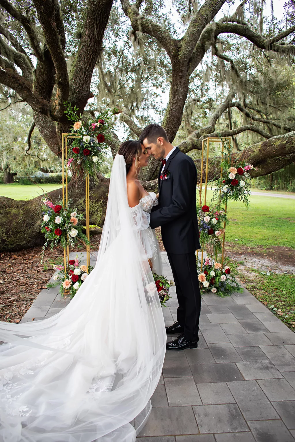 Gold Wedding Ceremony Tree Arch with Red Roses, Blue Thistle, Pink Roses, Peach Chrysanthemums, White Bacopa, and Greenery Decor Ideas | Tampa Bay Florist Save The Date Florida | Event Venue Legacy Lane Weddings | Brooksville Photographer Limelight Photography | Videographer Priceless Studios