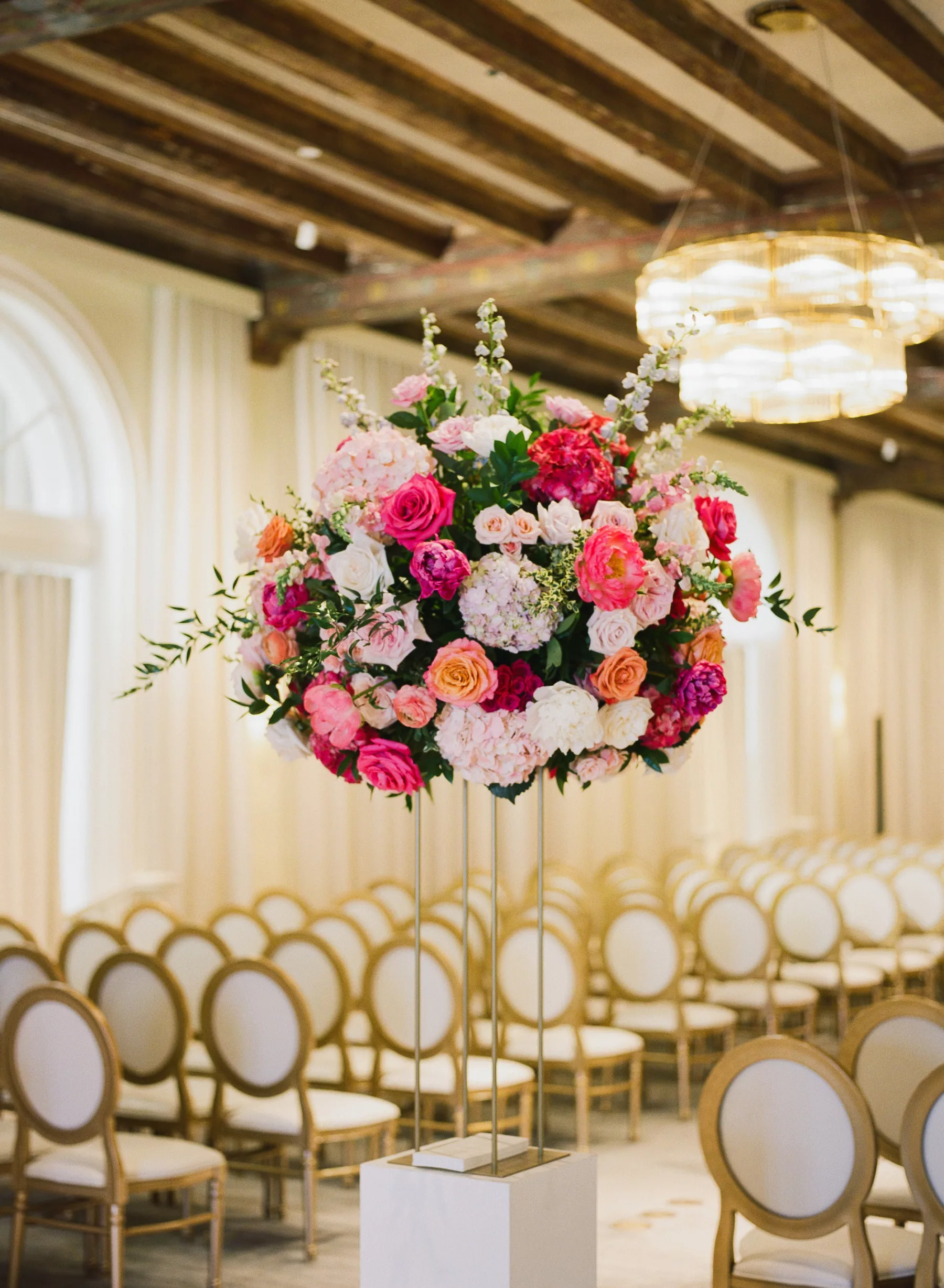 Luxurious Summer Ballroom Wedding Ceremony Aisle Decor | Tall Flower Stand with Pink Anemones and Hydrangeas, Orange Garden Roses, Blue Stock Flowers | Gold and White Chairs | Tampa Bay Florist Bruce Wayne Florals | Kate Ryan Event Rentals
