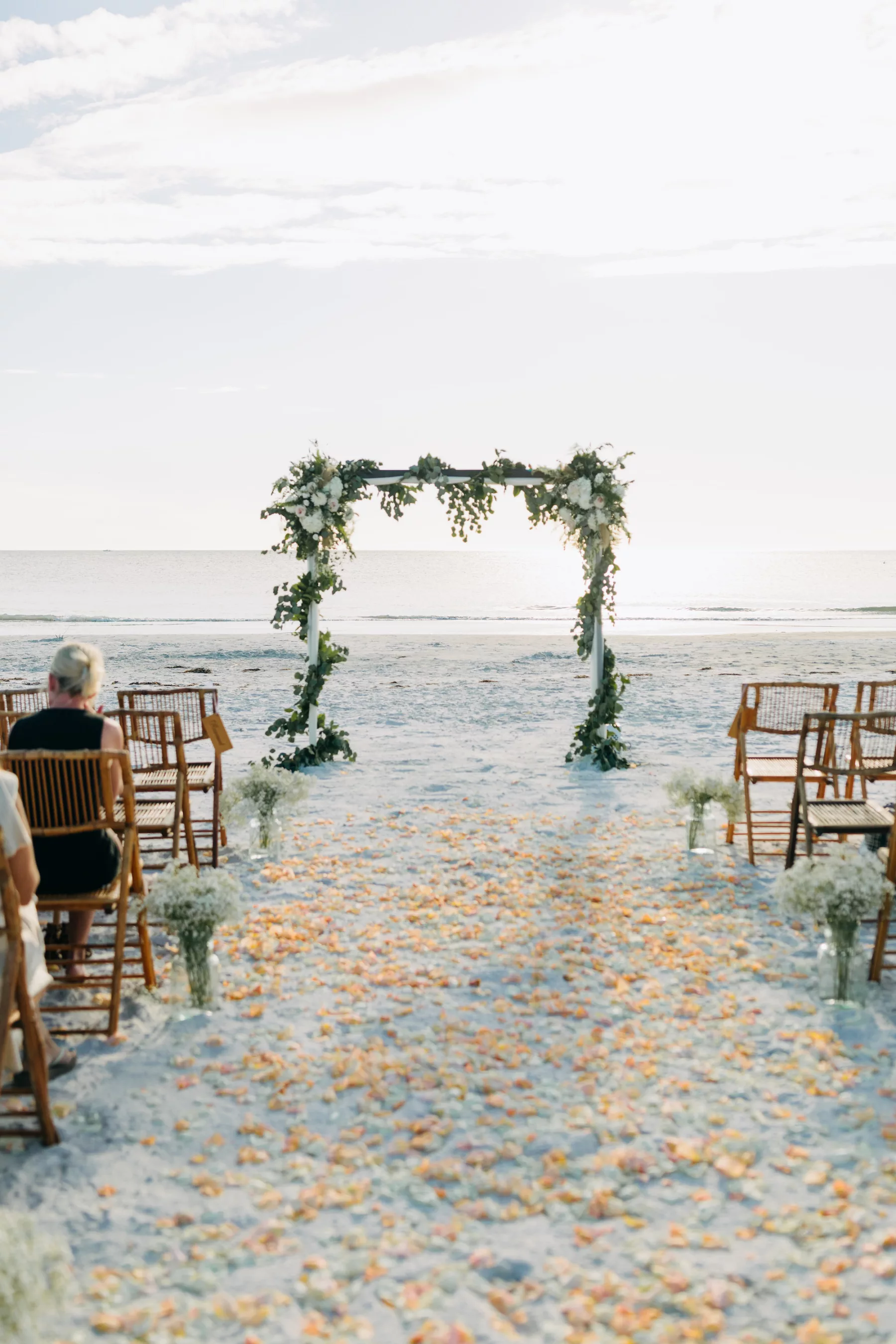 White Arbor with Wrapped Greenery Garland and White Roses for Fall Boho Beach Wedding Inspiration | Rose Petal Aisle Decor Ideas