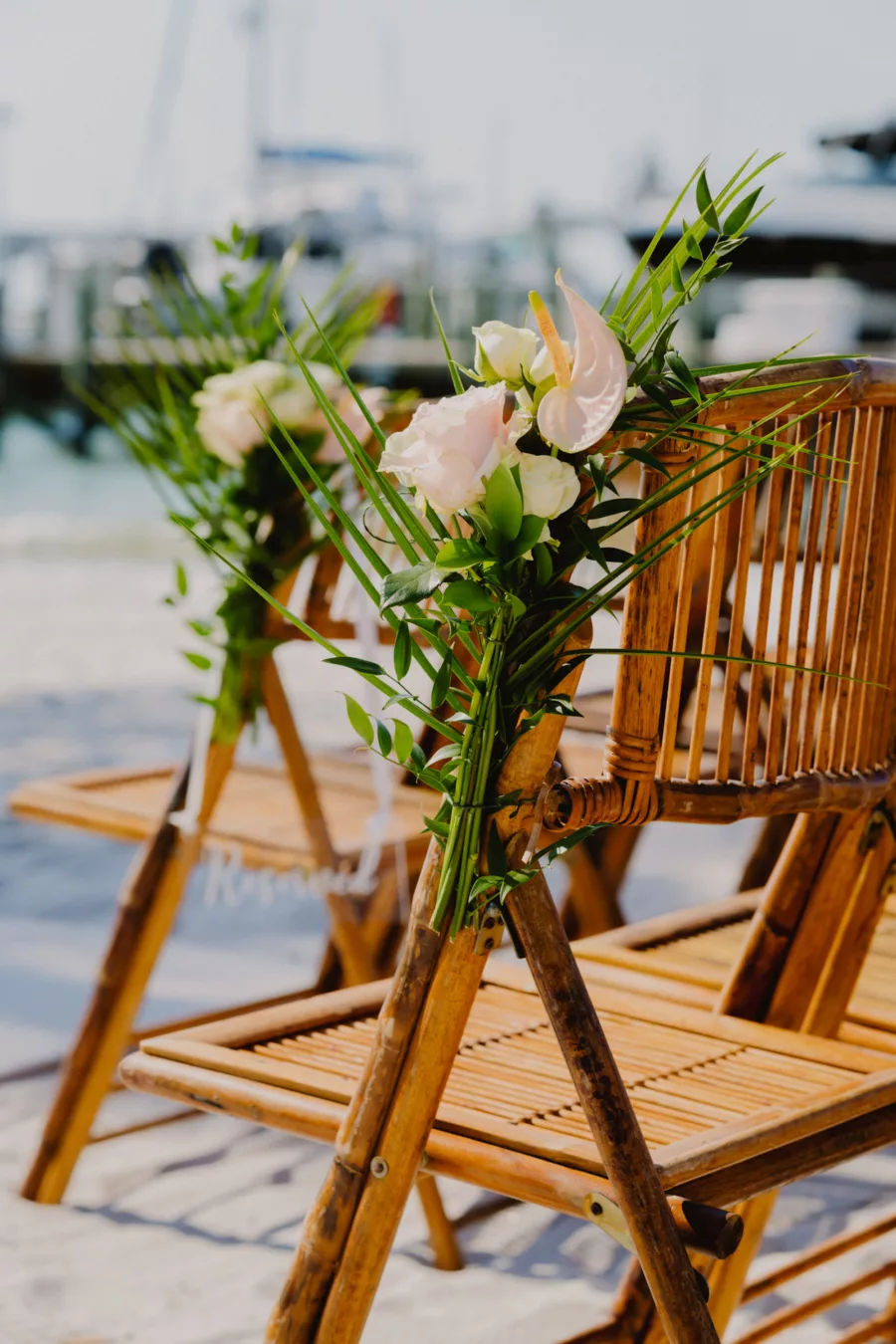 Tropical Pink Anthurium, White Roses, Palm Leaves, and Greenery Aisle Chair Decor Ideas | Bamboo Folding Chair Wedding Ceremony Seating Inspiration | St Pete Florist Monarch Events and Design