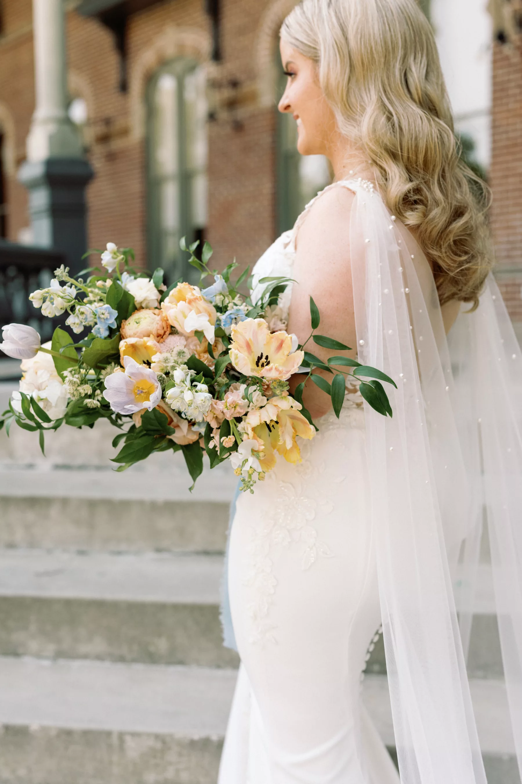 White Lace Fit and Flare Wedding Dress with Illusion Plunging Neckline and Open Back Inspiration | Pearl Veil Cape Ideas | Orange and Blue, and Greenery Spring Bouquet | Boutique Truly Forever Bridal Tampa | Photographer Dewitt For Love Photography
