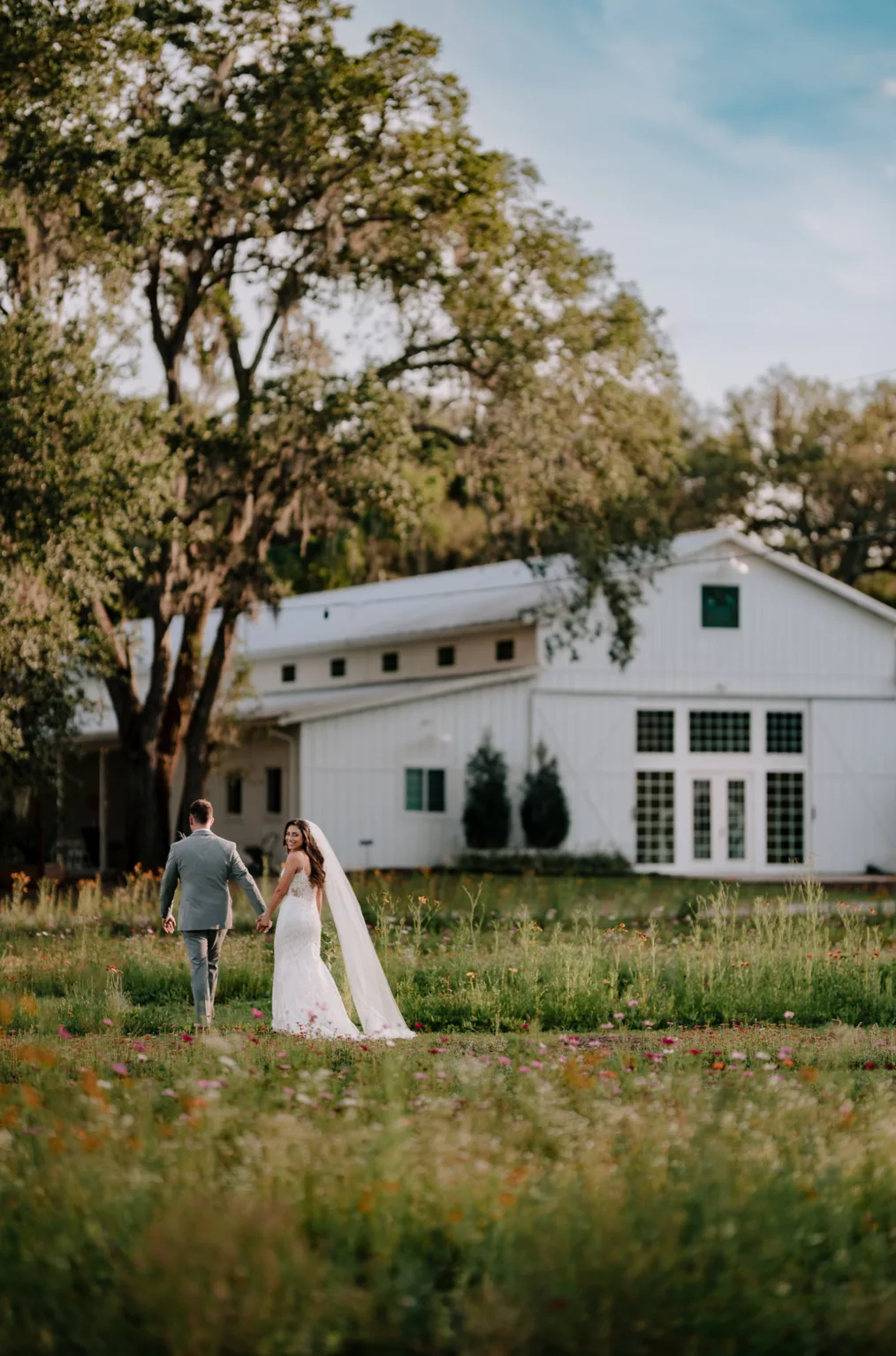 Bride and Groom Walking Through Wildflower Field Wedding Portrait | Rustic Barn Wedding Reception Inspiration | Florida Event Venue Ever After Farms Flower Wedding Barn | Tampa Wedding Photographer and Videographer Sabrina Autumn Photography