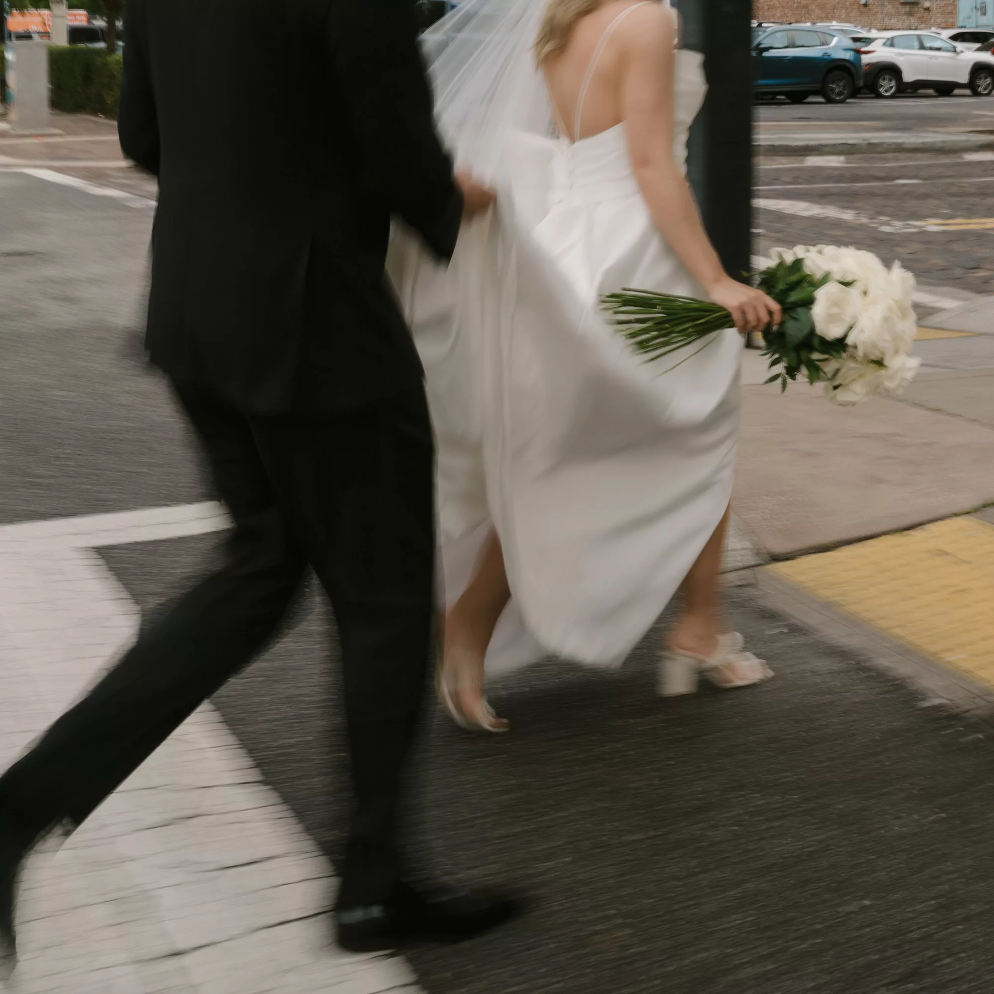 Groom Helping Bride with Wedding Dress Across the Street