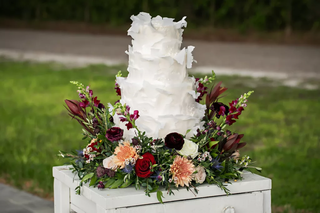 White Textured Round Four-Tiered Wedding Cake with Wafer Paper and Rice Paper Inspiration | Fall Cake Table Flower Arrangement Decor Ideas with Burgundy, White, and Pink Roses, Ginger Flower, Stock Flowers, Blue Thistle, and Greenery | Tampa Bay Florist Save The Date Florida