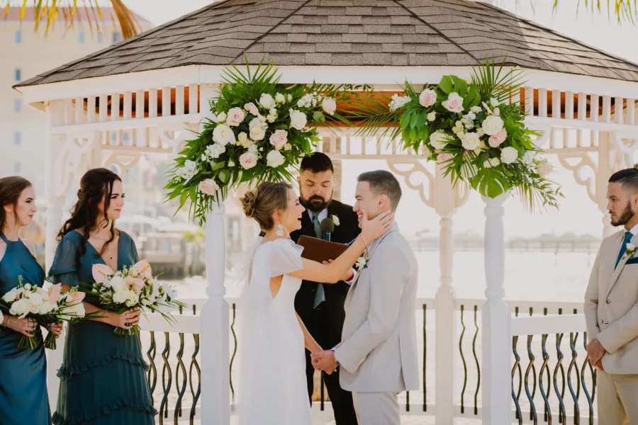 Bride and Groom Vow Exchange Tropical Beach Wedding Ceremony Inspiration| Tropical Pink and White Roses, Monstera, Palm Leaf Spring Wedding Reception Gazebo Decor Ideas | Tampa Bay Florist Monarch Events and Design | Waterfront St Pete Venue Isla Del Sol Yacht and Country Club | Photographer and Videographer Mars and the Moon Films