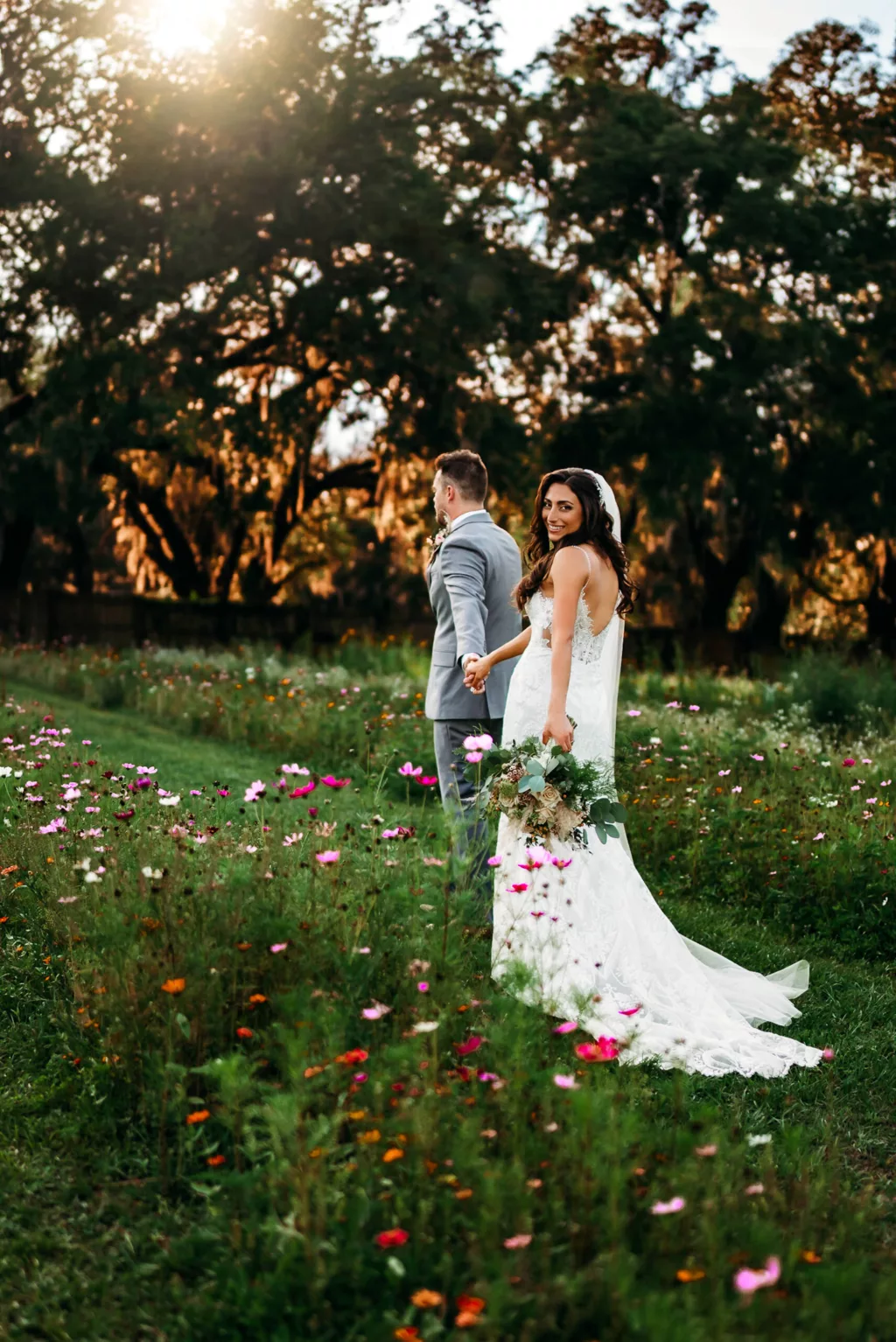 Bride and Groom Walking Through Wildflower Garden Sunset Wedding Portrait | Tampa Bay Photographer Sabrina Autumn Photography | Florida Event Venue Ever After Farms Flower Wedding Barn