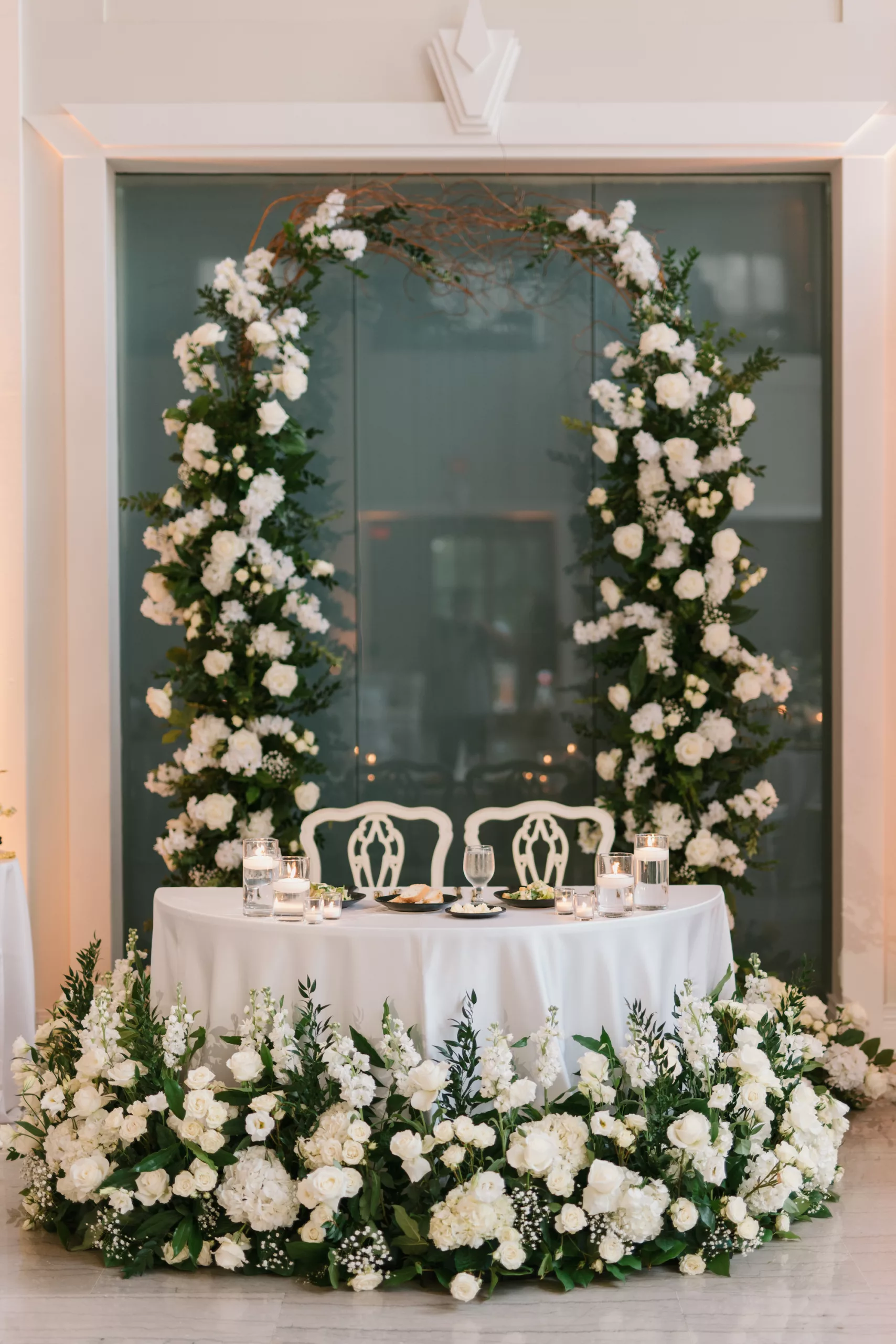 Classic Wedding Reception Sweetheart Table Inspiration | White Roses, Hydrangeas, Baby's Breath, and Greenery Floral Arrangement Backdrop Ideas