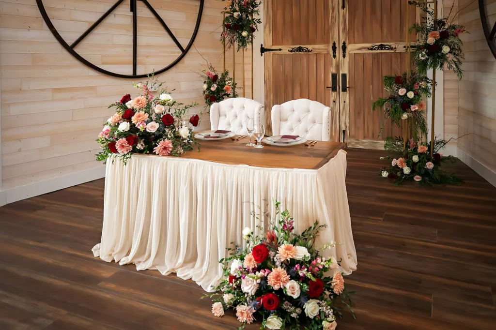 Peach Chrysanthemums, Red and Pink Roses, Ginger Flower, White Bacopa, and Greenery Floral Arrangement for Sweetheart Table with Ivory Table Skirt Decor Ideas | Tampa Bay Florist Save The Date Florida