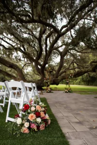 Elegant Outdoor Wedding Ceremony Tree Inspiration | Peach Chrysanthemums, Red and Pink Roses, Ginger Flower, White Bacopa, and Greenery Aisle Floral Arrangement Decor Ideas | Tampa Bay Florist Save The Date Florida | Event Venue Legacy Lane Weddings