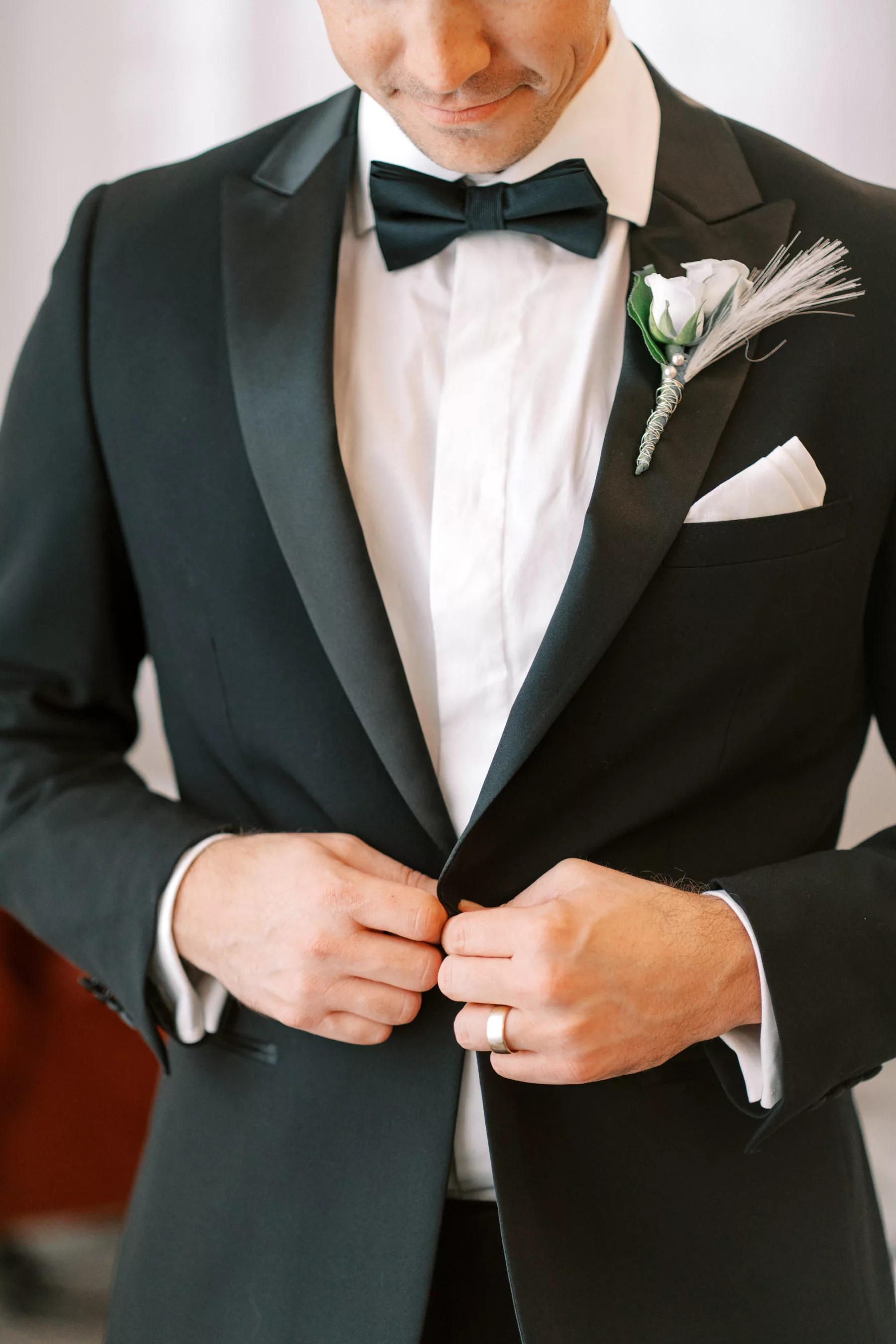 Black Tuxedo With Bow-tie Groom's Wedding Day Attire Inspiration | White Rose and Feather Great Gatsby Inspired Boutonniere Ideas | Men's Attire Suitshop