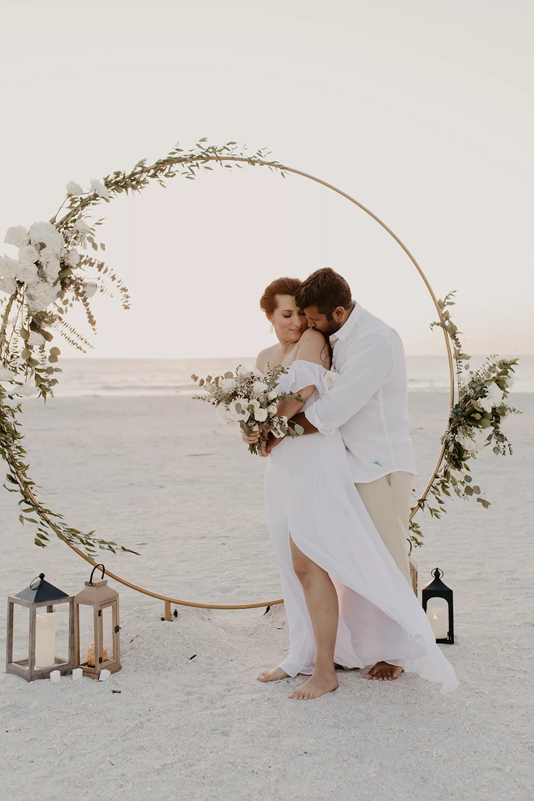 Intimate Boho Beach Wedding Ceremony Elopement Decor Ideas | Round Gold Arch with White Roses, Baby's Breath, Greenery, and Lanterns | Tampa Bay Florist Lemon Drops