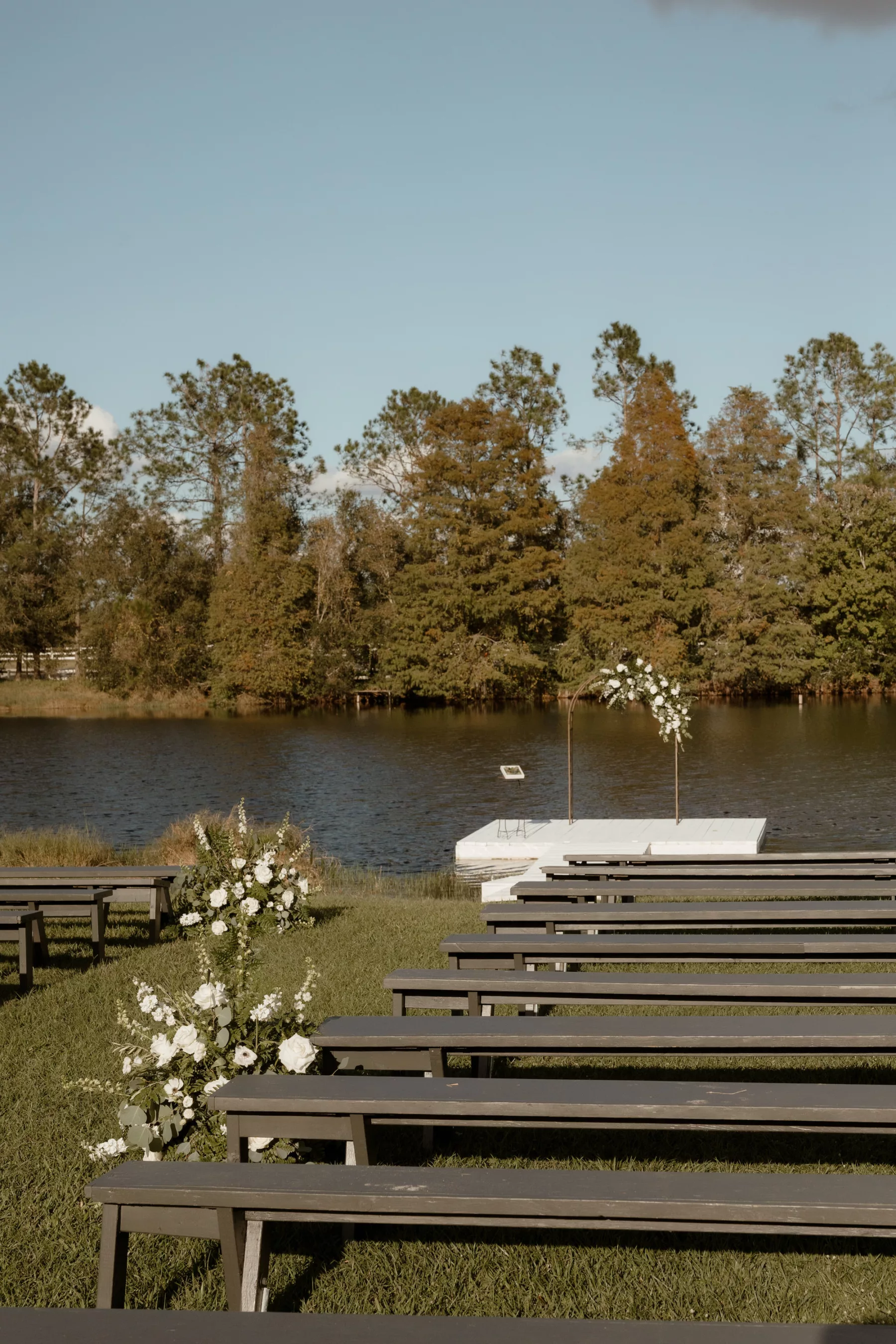 Waterfront Dock Fall Wedding Ceremony Decor Ideas | Bench Seating | White Roses, Anemone, Stock Flowers, and Greenery Aisle Floral Arrangement Inspiration