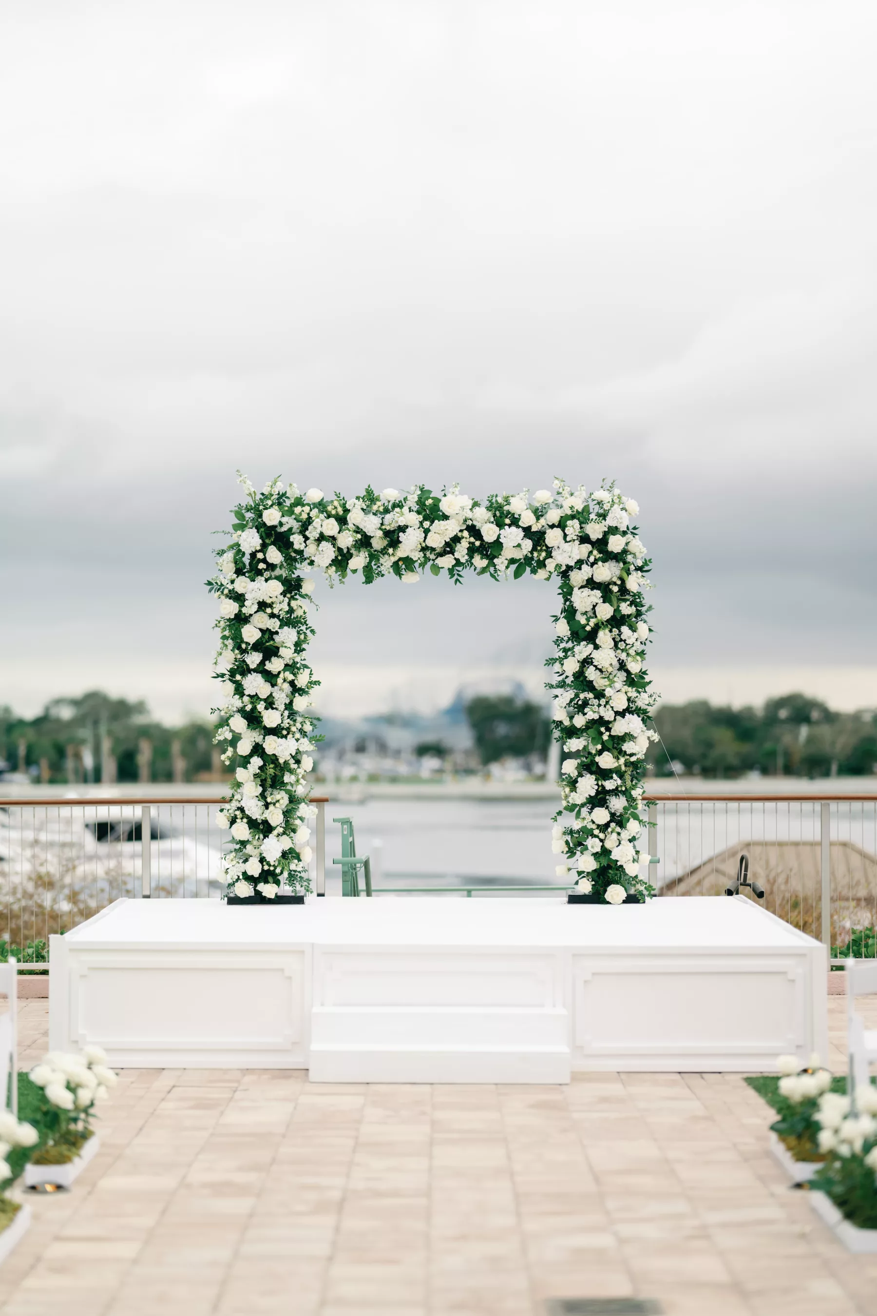 Timeless Outdoor Waterfront Winter Wedding Ceremony with White Rose and Greenery Arch and Stage Inspiration | St Pete Historic Hotel Venue The Vinoy