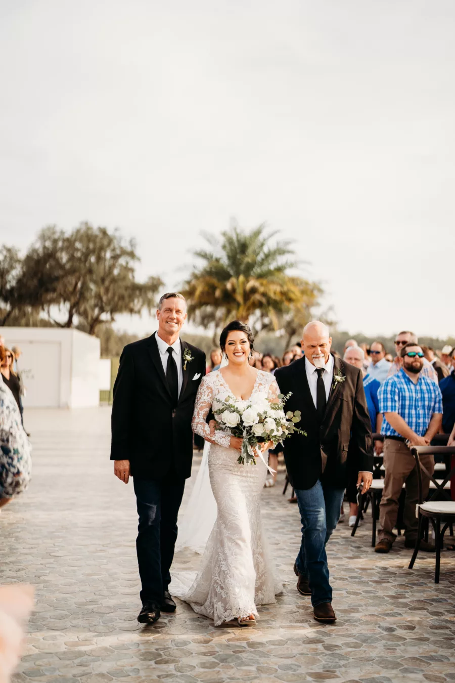 Bride Walking with Father and Stepfather Down Wedding Aisle
