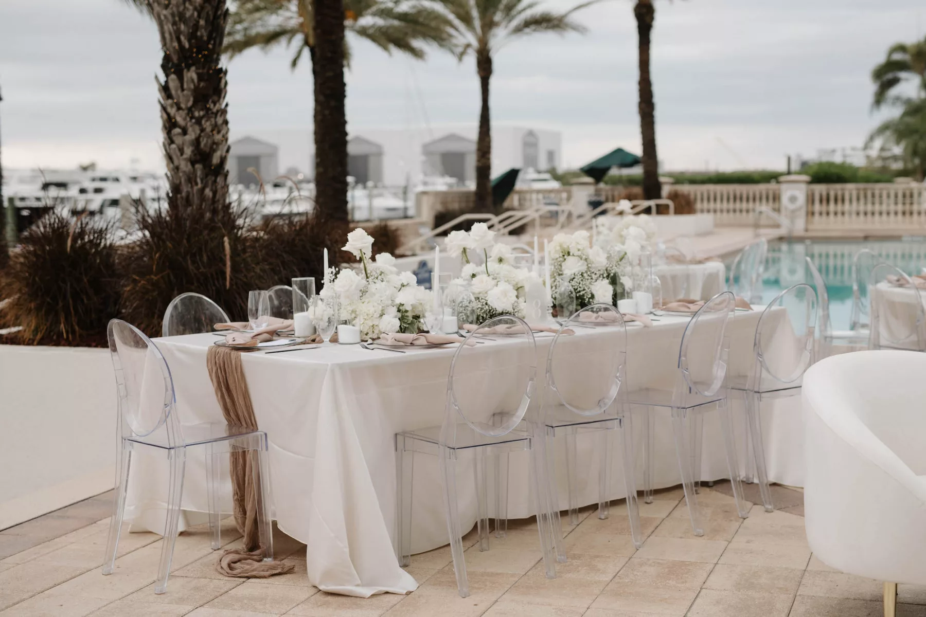 Modern Oceanview Poolside Monochromatic Spring Wedding Reception Tablescape Ideas | Acrylic Ghost Chairs | White Roses and Baby's Breath Centerpiece Inspiration | Tampa Bay Kate Ryan Event Rentals | Venue Westshore Yacht Club
