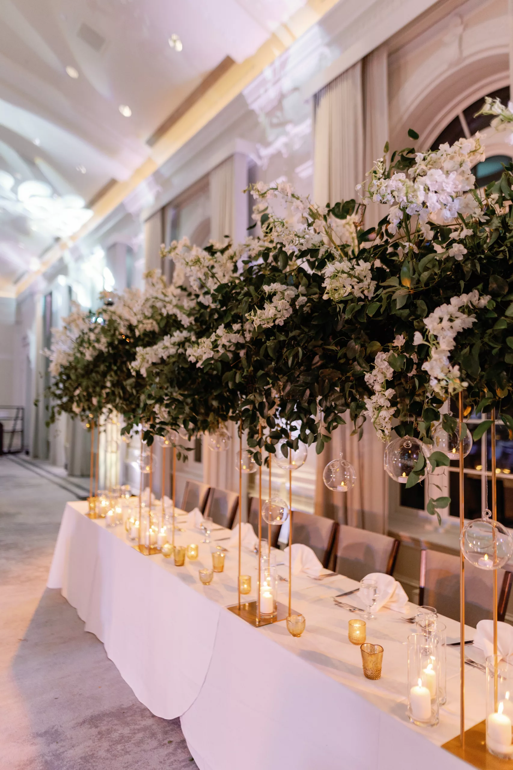 Luxurious White and Gold Grand Ballroom Wedding Reception Head Table Decor Ideas | Hanging Glass Vase Globe Tealight Candle Holder, Long White Feasting Table, Tall Gold Floral Stand with Cascading Greenery and White Flowers | Tampa Bay Event Planner Coastal Coordinating